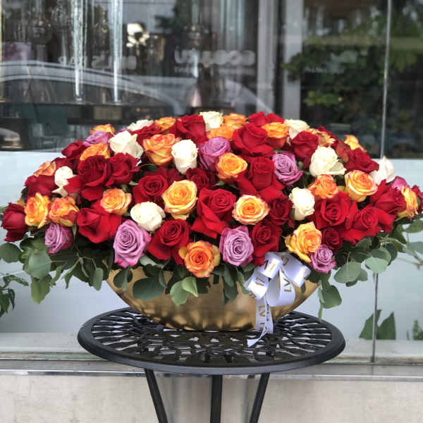 Large mixed rose arrangement in a gold bowl on a black stand