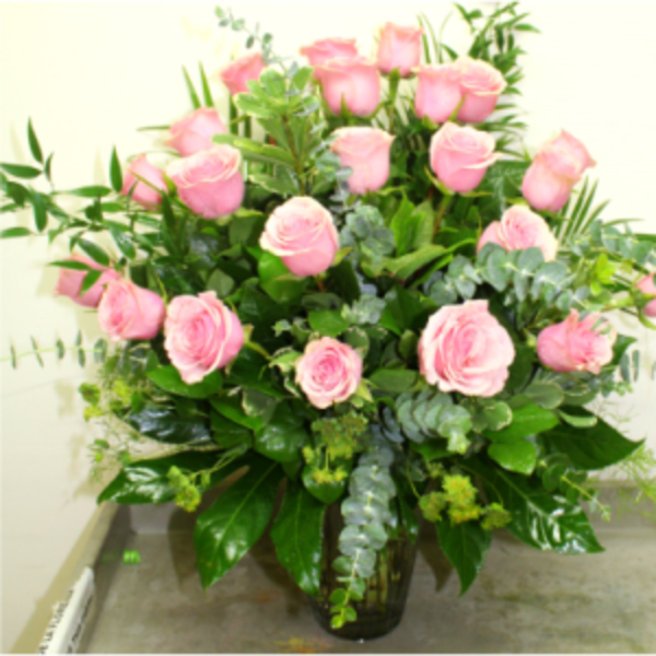 Pink roses arranged in a clear glass vase with greenery