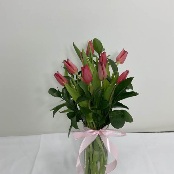 Pink tulips in a clear glass vase tied with a pink ribbon