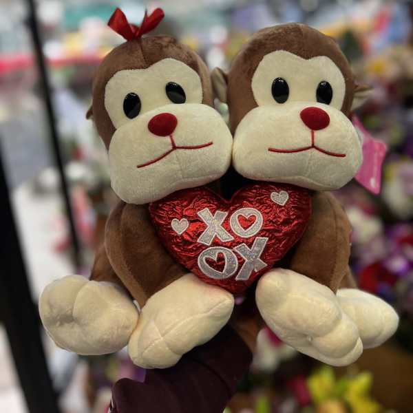 Two plush monkeys holding a red heart with XOXO lettering