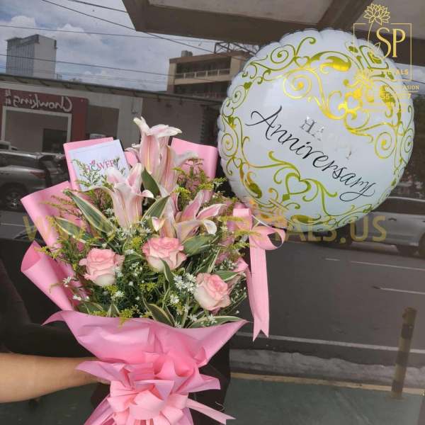 Pink bouquet with roses and lilies beside a white anniversary balloon