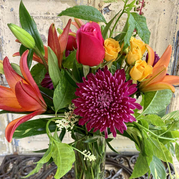 Bouquet of roses, lilies, and a chrysanthemum in a glass vase
