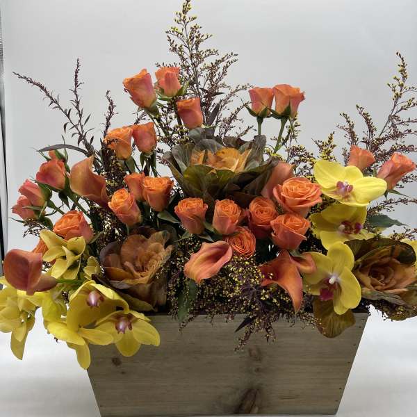 Orange roses and yellow orchids arranged in a wooden box
