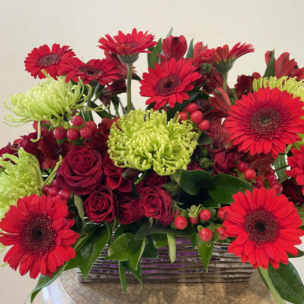 Red gerbera daisies and roses in a rectangular basket with green mums