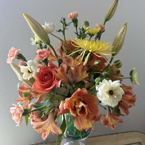 Mixed bouquet of coral, white, and yellow flowers in a glass vase