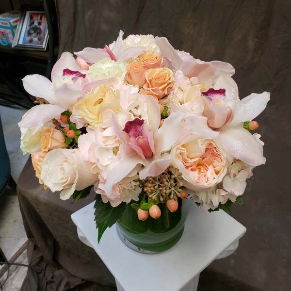 Blush and cream bouquet with roses and orchids in a glass vase