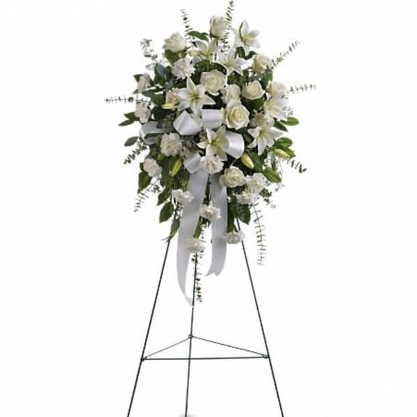 White floral standing spray on an easel with ribbon streamers