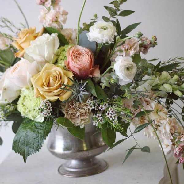 Mixed bouquet of roses and ranunculus in a silver vase
