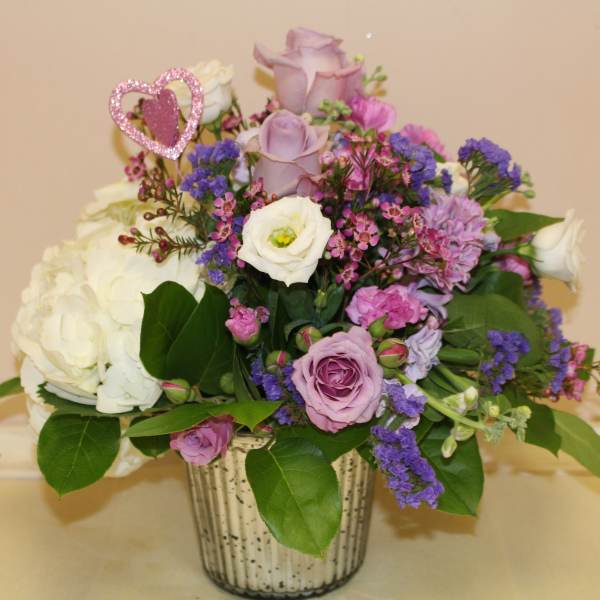Lavender and white rose arrangement in a silver vase with a pink heart pick