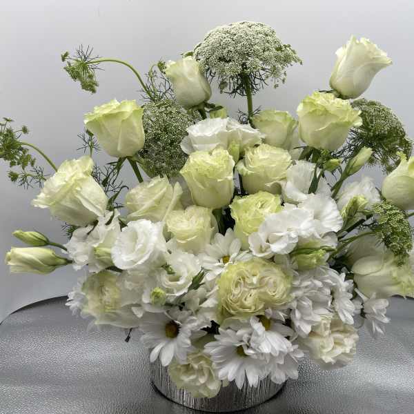 White and pale green floral arrangement in a silver vase