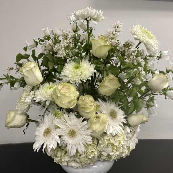 White roses and daisies arranged in a white vase