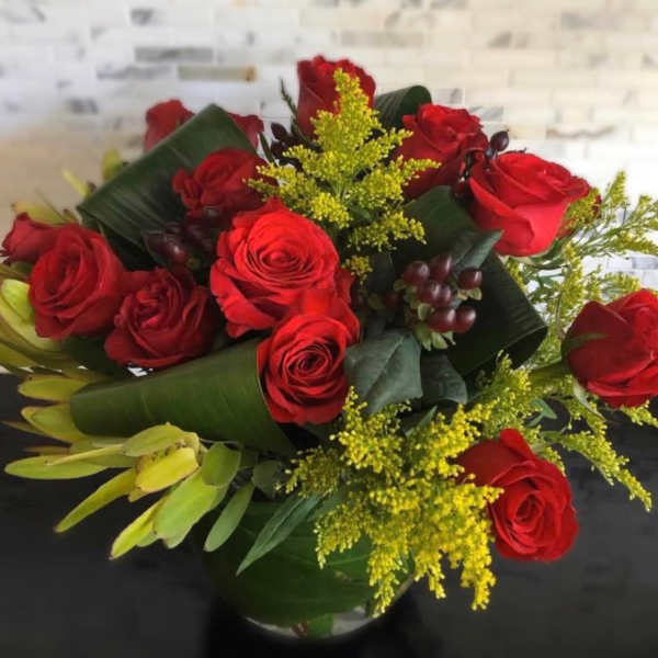 Bouquet of red roses with yellow filler in a glass vase