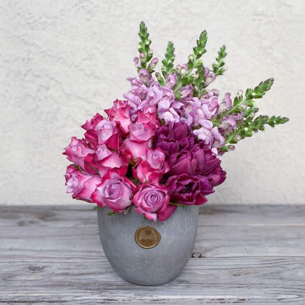 Pink and purple flowers arranged in a gray vase