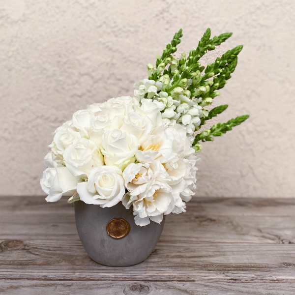 White floral arrangement in a gray vase with green spikes