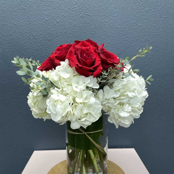 Red roses and white hydrangeas in a clear glass vase