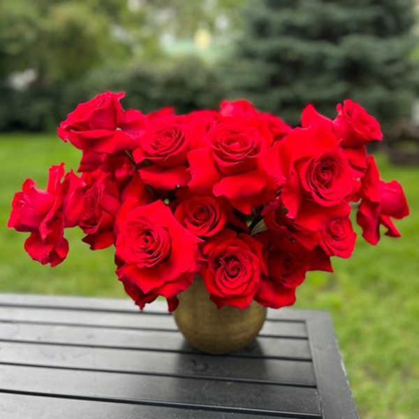Bouquet of red roses in a round vase on an outdoor table