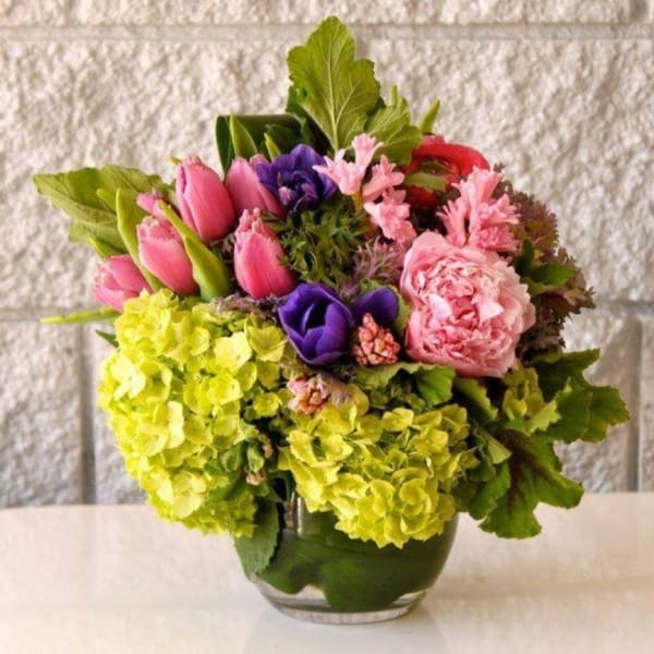 Mixed bouquet in a glass vase with pink, purple, and lime flowers