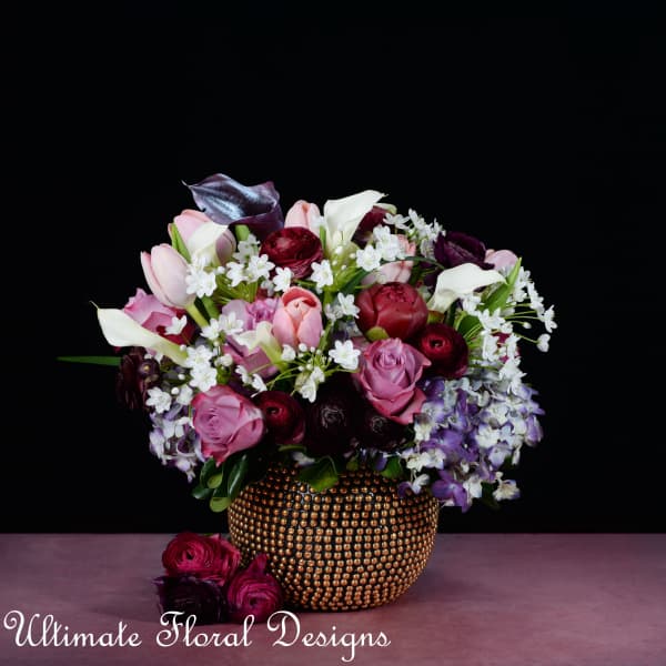 Pink and white flowers arranged in a gold beaded vase.