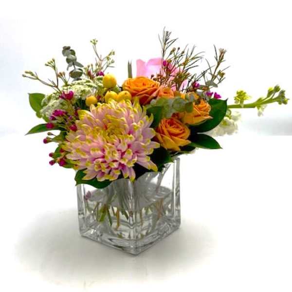 Bouquet of orange and pink flowers in a clear square vase