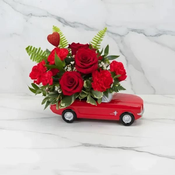 Red rose and carnation arrangement on a red toy car