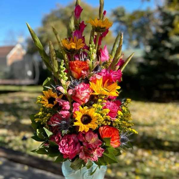 Tall mixed bouquet in a light blue vase with bright pink and yellow flowers