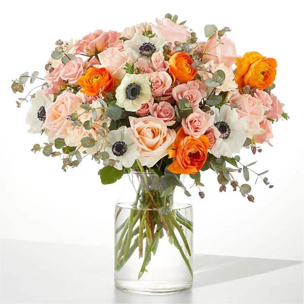 Bouquet of pink, white, and orange flowers in a clear glass vase