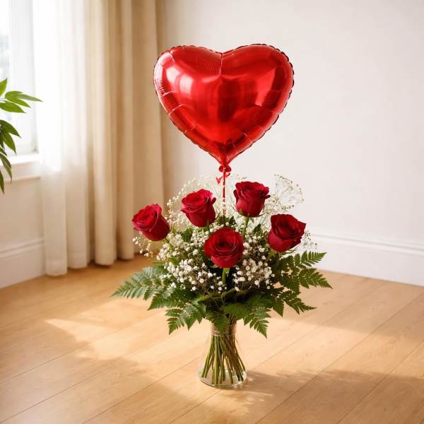 Red roses in a glass vase with a heart-shaped balloon