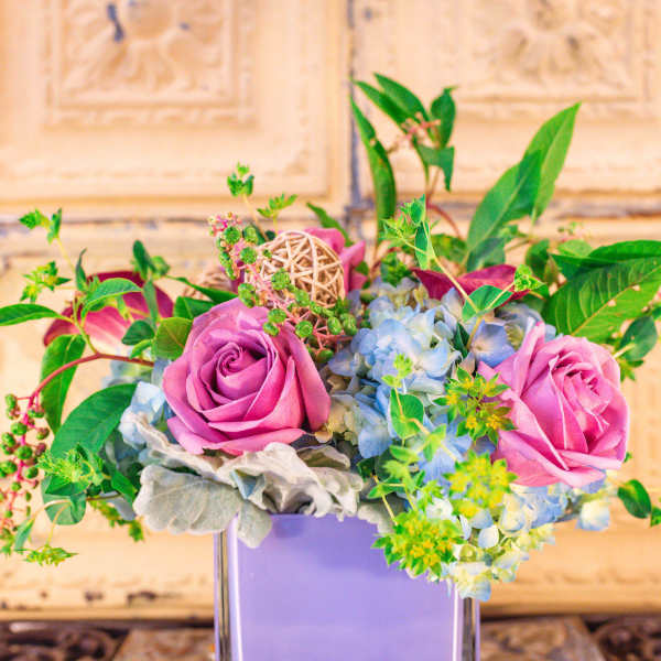 Pink roses and blue hydrangeas in a lavender vase