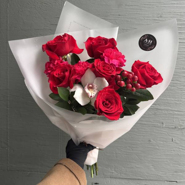 Bouquet of red roses with white orchids wrapped in white paper