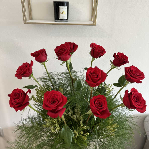 Arrangement of red roses with airy greenery in a vase