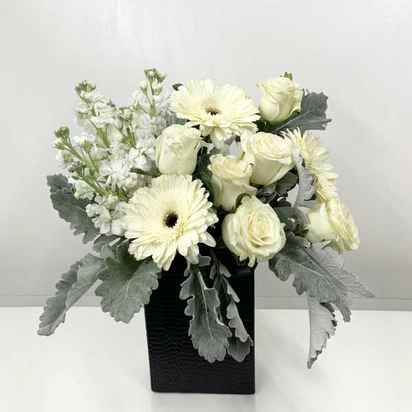 White roses and gerbera daisies in a black vase