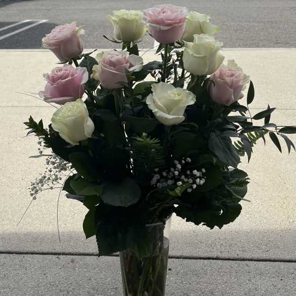 Pink and white roses arranged in a clear glass vase
