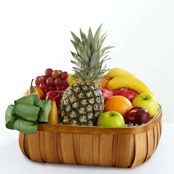 Fruit basket with pineapple, bananas, apples, grapes, and pears in a wooden basket