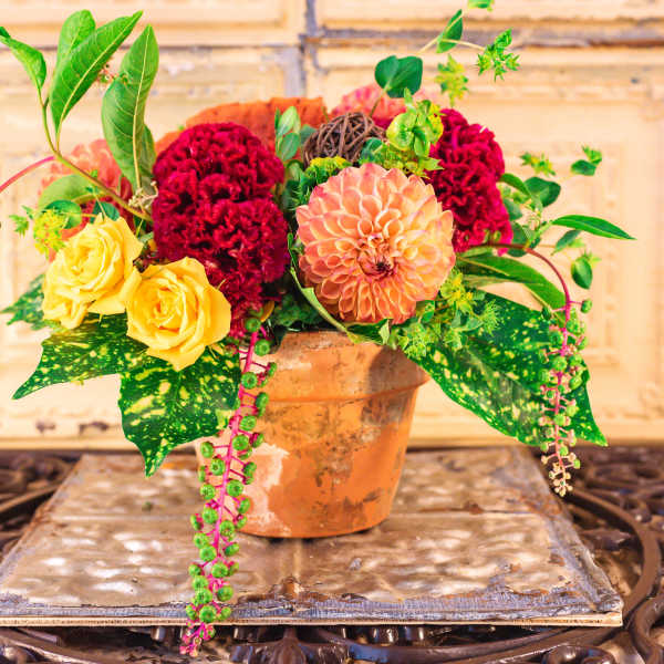 Mixed bouquet in a terracotta pot with yellow roses and red blooms