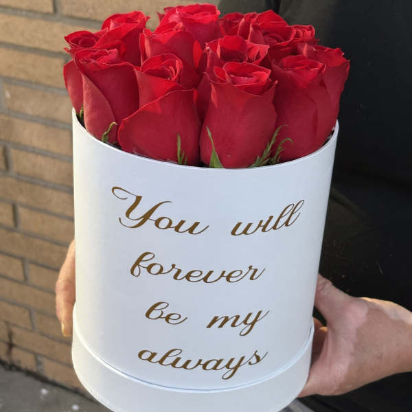 Red roses in a white round box with gold text
