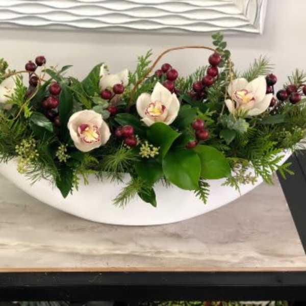 Low floral centerpiece with white orchids and red berries in a white bowl