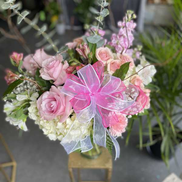 Pink rose bouquet with white flowers and a bright ribbon in a glass vase