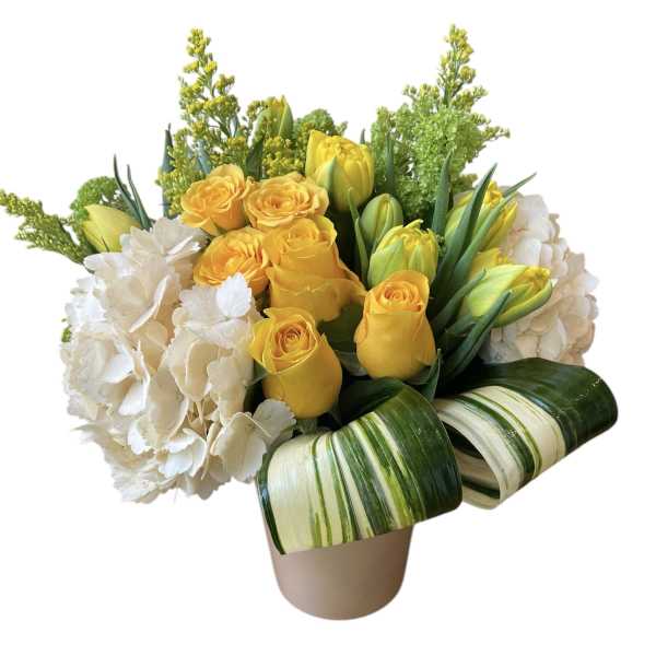 Yellow roses and white hydrangeas in a beige vase with striped leaves