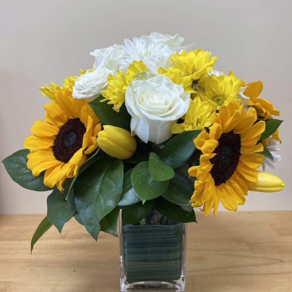 Sunflowers and white roses in a clear square vase
