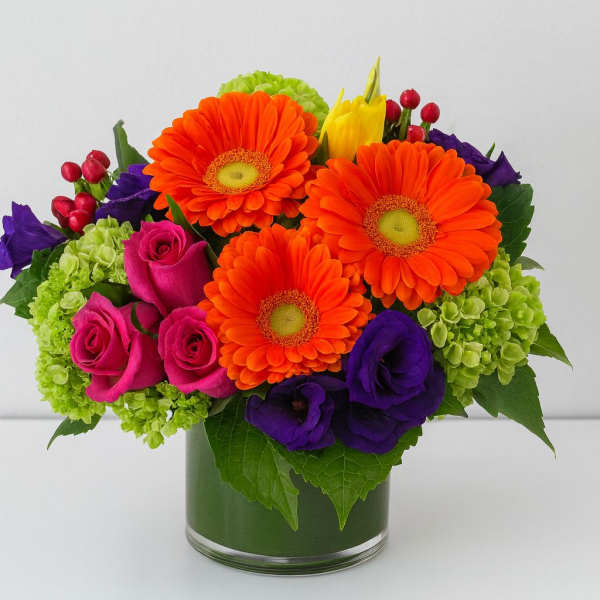Bright mixed bouquet in a glass vase with orange daisies and pink roses