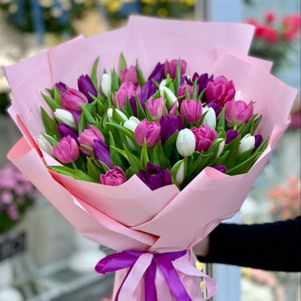 Bouquet of pink, purple, and white tulips wrapped in pink paper
