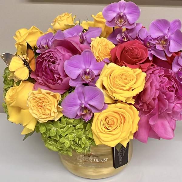 Bright bouquet of yellow and pink roses with purple orchids in a gold vase