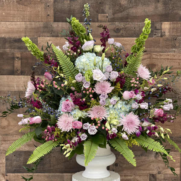 Large pastel floral arrangement in a white pedestal vase