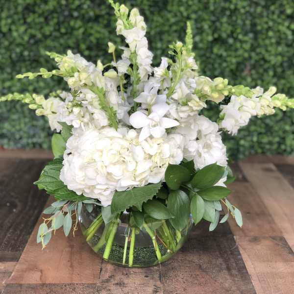 White floral arrangement in a clear glass bowl vase