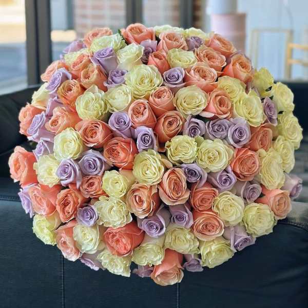 Large round bouquet of pastel roses in peach, lavender, and pale yellow
