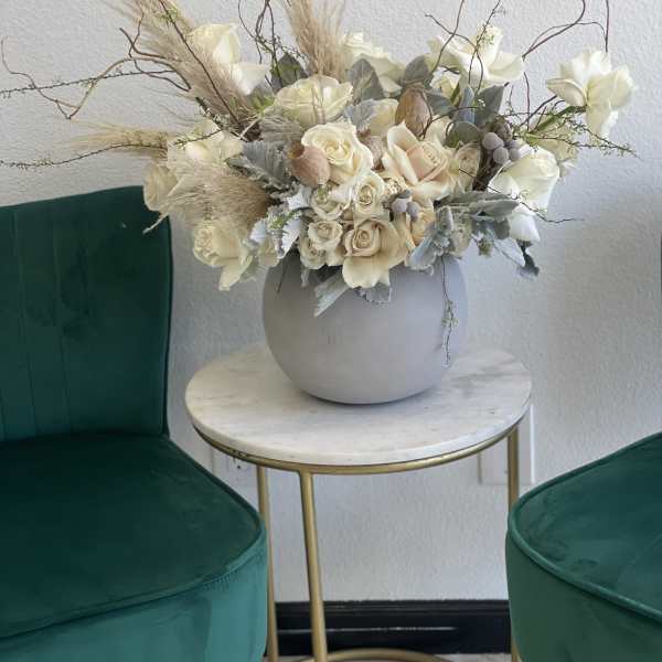 Cream floral arrangement in a round gray vase with tall dried branches