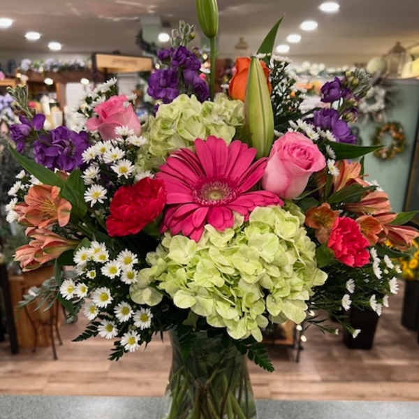 Mixed bouquet in a glass vase with pink, purple, green, and white flowers