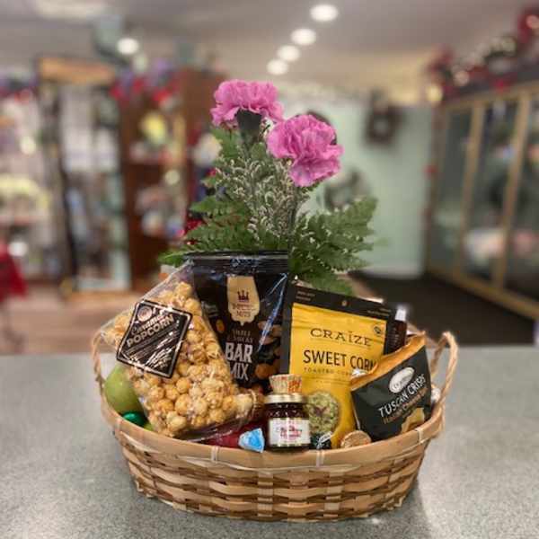 Gift basket with snacks and pink flowers in a woven basket