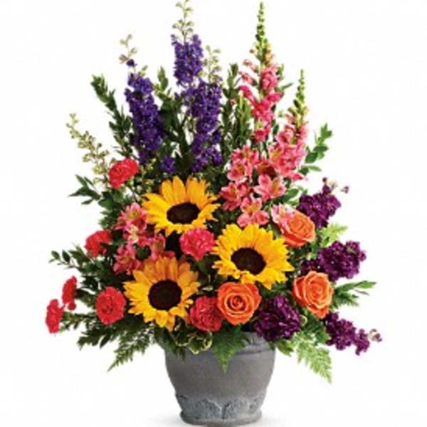 Colorful flower arrangement in a gray vase with sunflowers, roses, and tall purple blooms