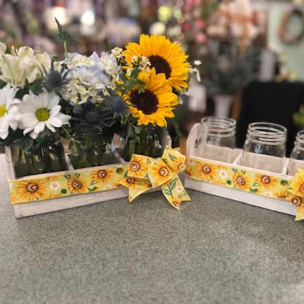 Sunflower and daisy arrangements in mason jars on a tray with sunflower ribbon
